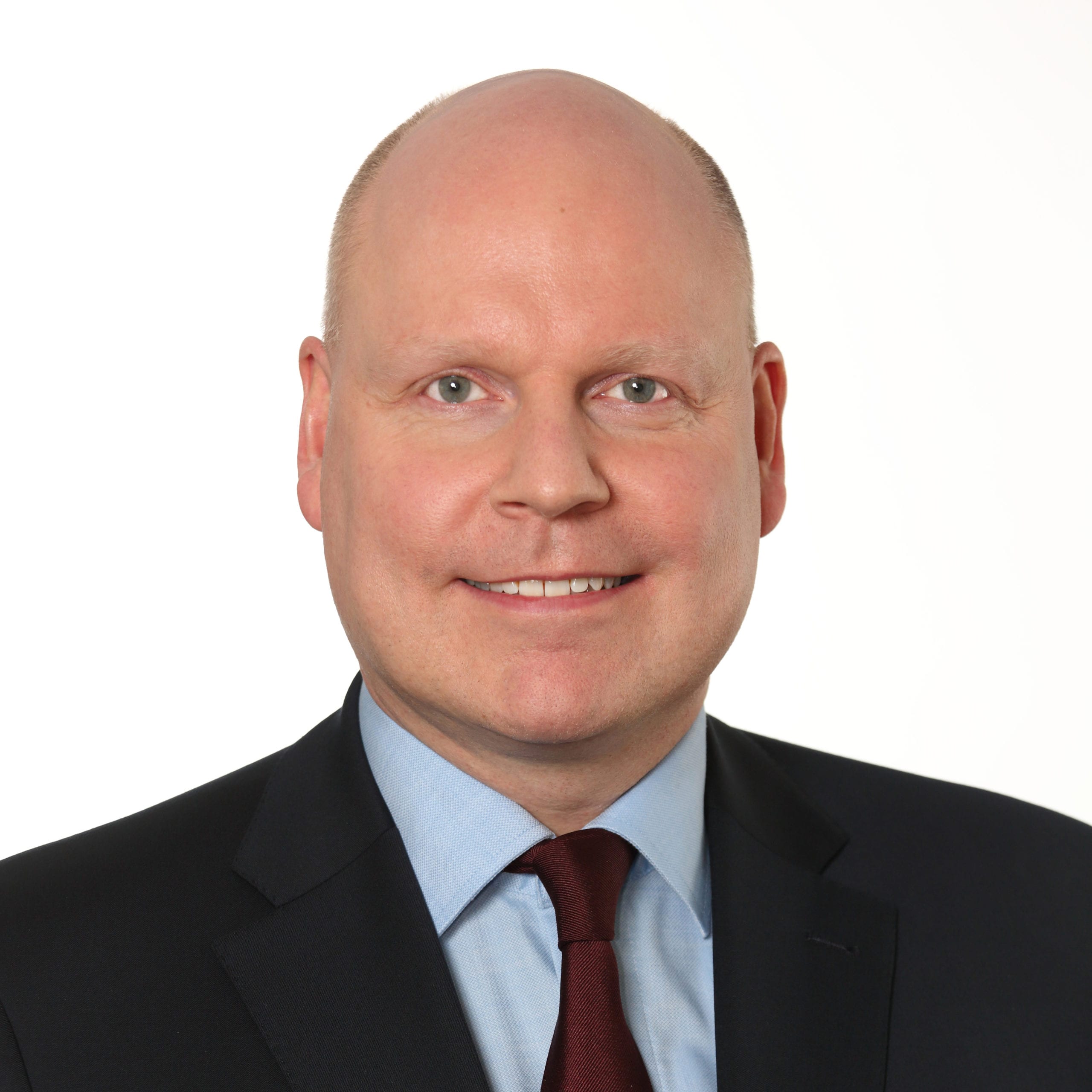 Headshot of Michael Gerke smiling and wearing a black suit with a blue shirt