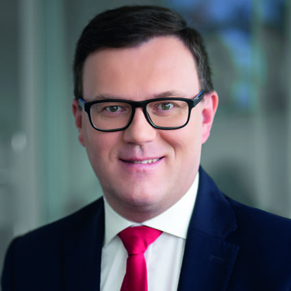 Headshot of Jaroslaw Czechowicz, wearing glasses and a black suit with a red tie.