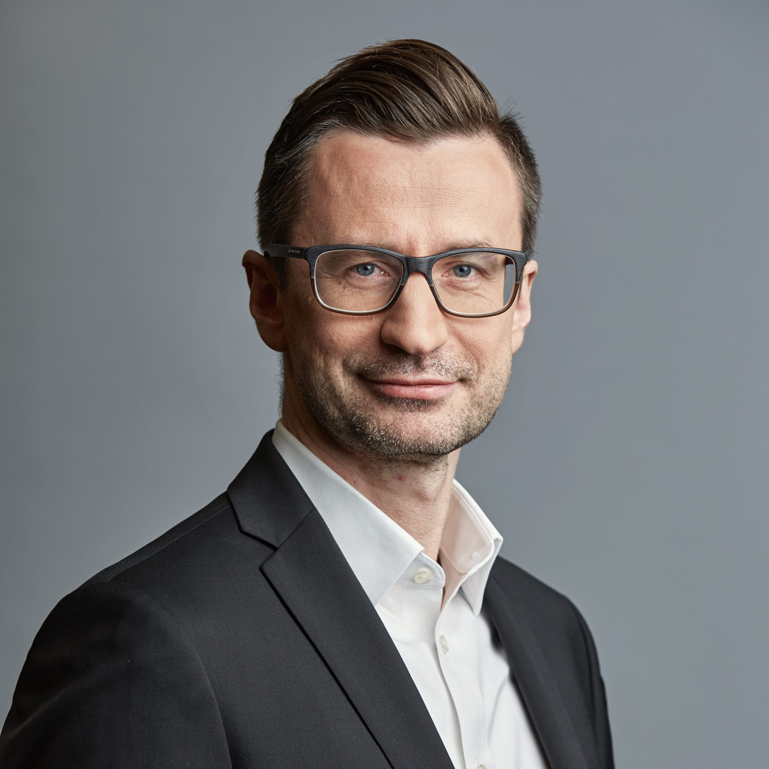 Headshot of Marcin Duda wearing a black suit with a white shirt.
