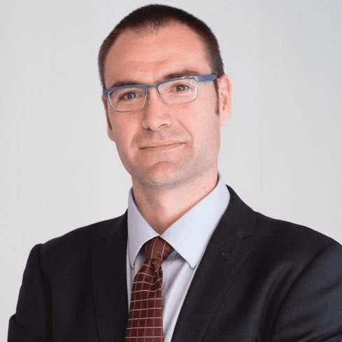 Headshot of Sergio wearing glasses and a black suit.