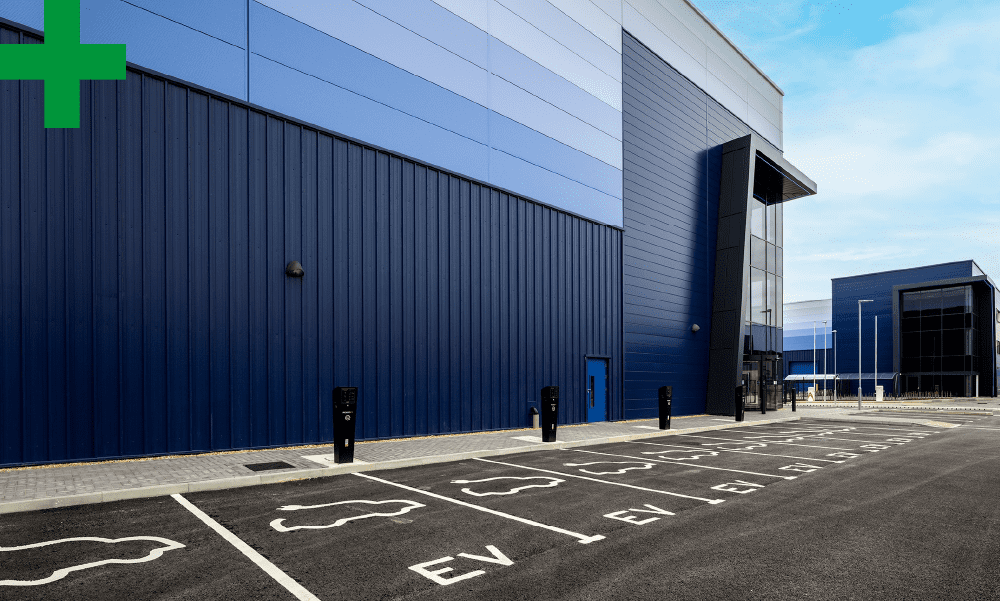 Warehouse with electric vehicle charging points outside.